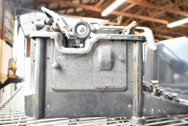 Remington countertop typewriter, vintage model, showing wear and patina. Features visible knobs and metal components.