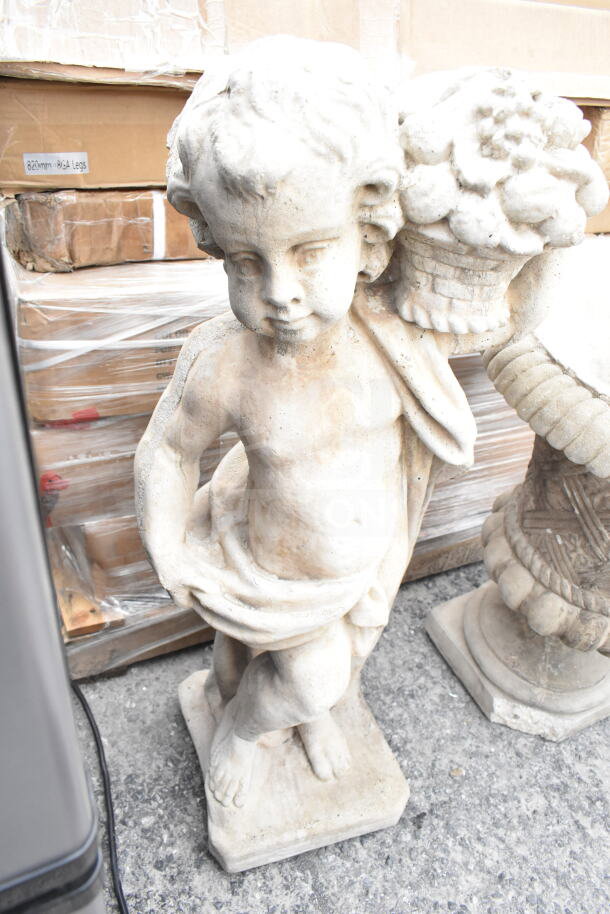 Stone cherub statue with basket detail, standing on a square base. Appears in good condition, rustic finish.