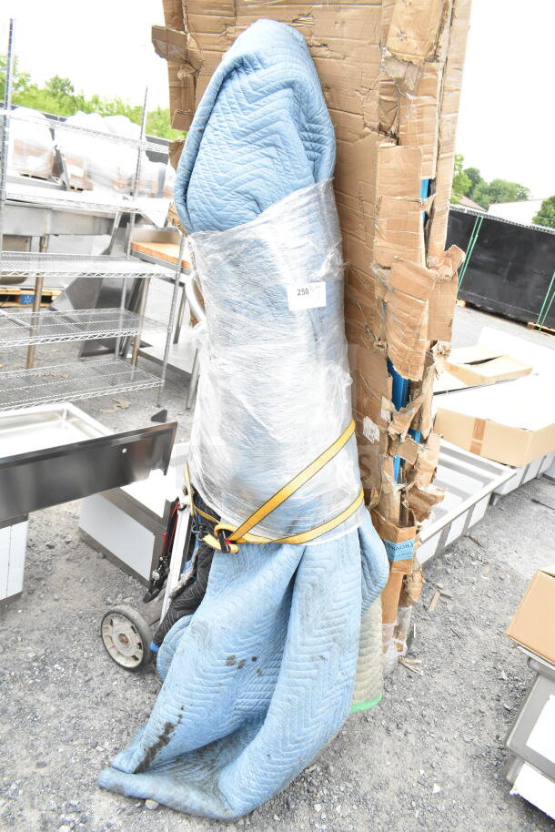 Wrapped stone statue with label "250" on protective covering, indicating size or lot number. Statue condition hidden; fragile packaging.