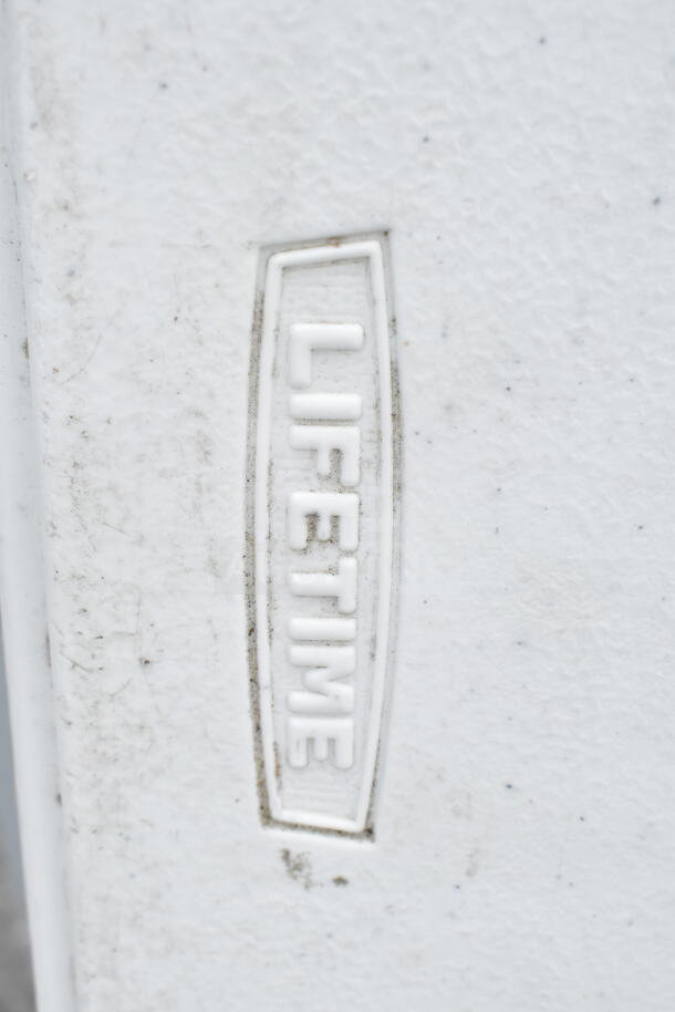 "Lifetime Bi Fold Folding Table showing embossed brand logo, minor surface wear visible, sturdy construction."