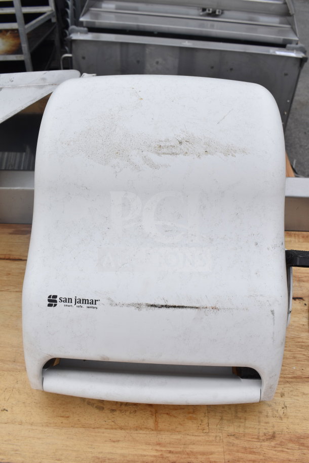 Butcher block table with under shelf, showing a San Jamar paper dispenser on top. Table surface shows signs of wear.