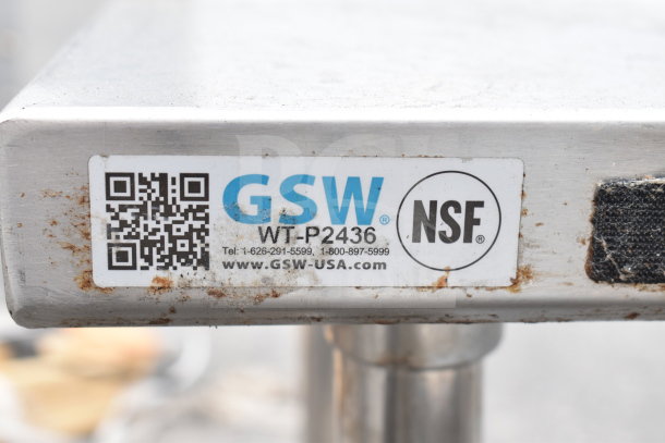 Metal table labeled GSW WT-P2436, NSF certified, with visible wear, QR code, and contact info. Includes under shelf.