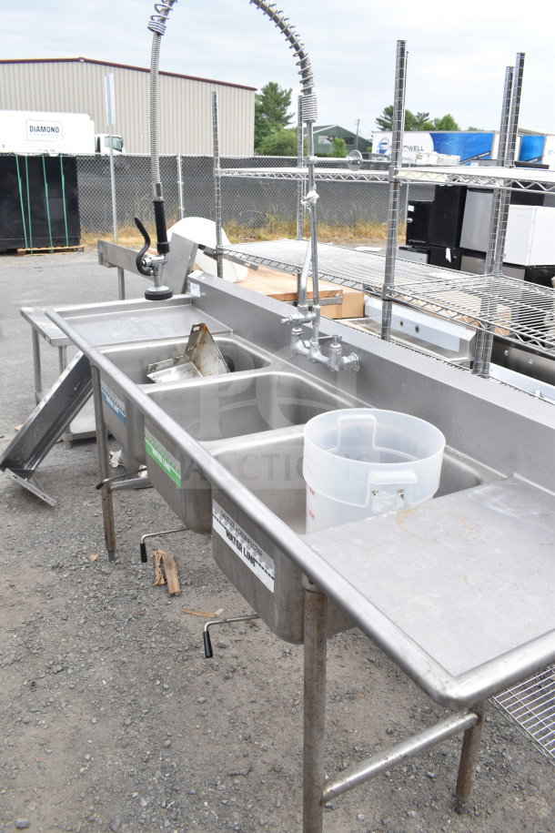 Commercial 3 bay sink with dual drain boards, faucet, and spray nozzle attachment; stainless steel, good condition.