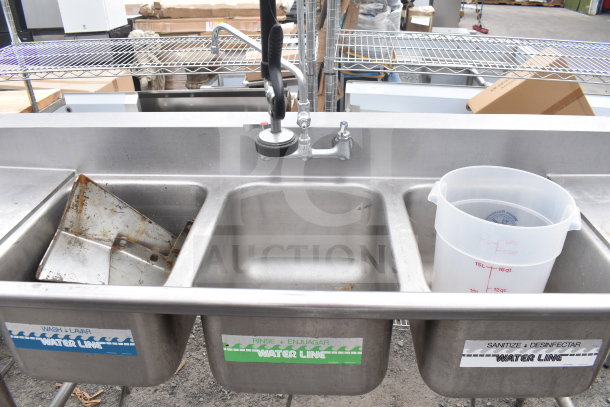 Commercial 3 bay sink with dual drain boards, faucet, and spray nozzle. Includes labeled water lines for wash, rinse, sanitize.