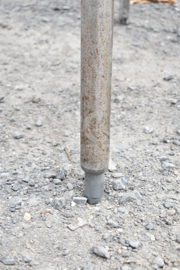 Rusty pipe embedded in gravel, showing signs of wear and exposure.