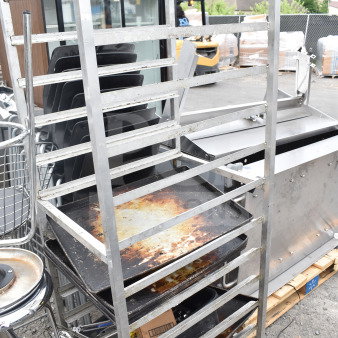 Commercial pan transport rack with multiple shelves, visible wear, and sturdy commercial casters; ideal for kitchen use.