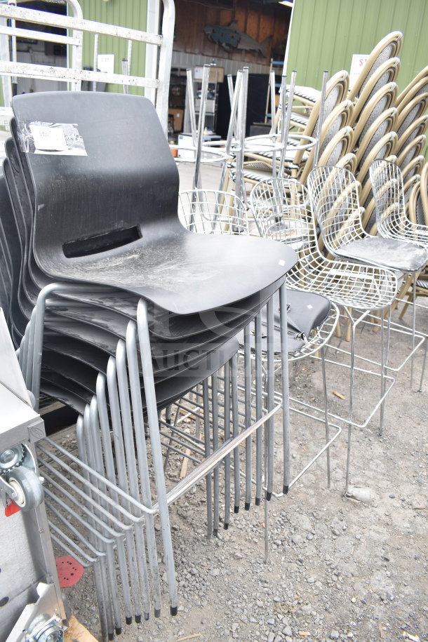 Stack of 12 modern chairs, including black chairs with chrome legs and wire chairs. Slightly worn condition.