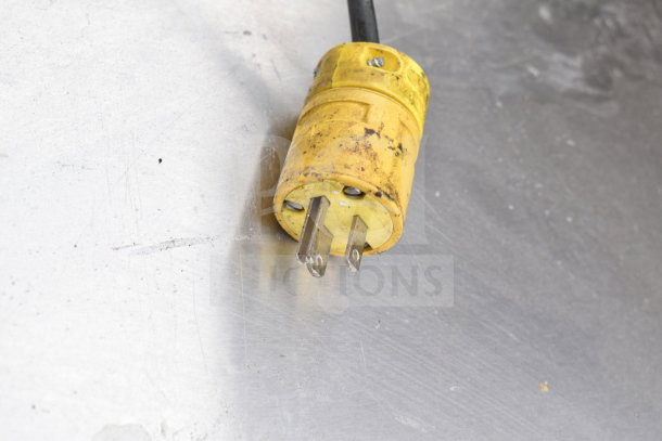 True TPP-67 Commercial Pizza Prep Table plug, showing a yellow three-prong plug on a metallic surface. No lids included.