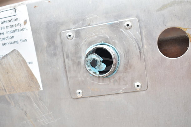Stainless steel panel of a commercial gas-powered pizza oven, featuring a pipe fixture with blue residue.