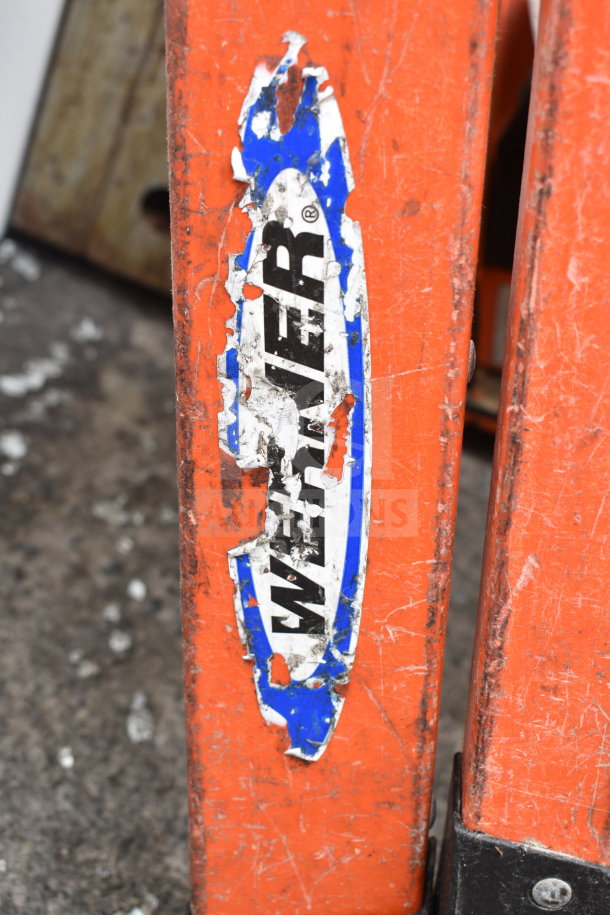 Werner A Frame Ladder with worn blue and white label. Orange frame, visible wear marks indicating previous use.