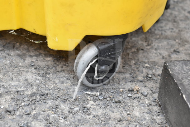 Yellow poly mop bucket with wringing attachment, black caster wheel shown, light wear visible on surface. Suitable for cleaning tasks.