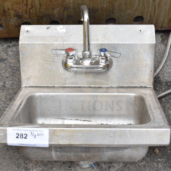 Commercial single bay wall mount sink with faucet and handles, stainless steel, shows moderate wear, label indicating item number 282.