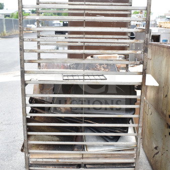 Commercial pan transport rack with multiple shelves, on sturdy commercial casters, visible wear and rust.