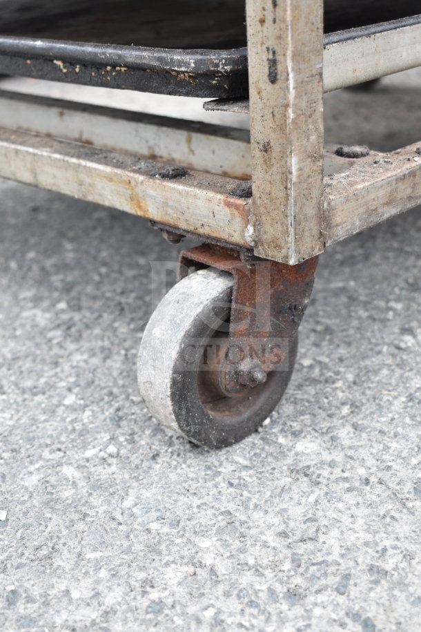 Commercial pan transport rack on heavy-duty casters, metal frame, worn condition, suitable for kitchen storage.