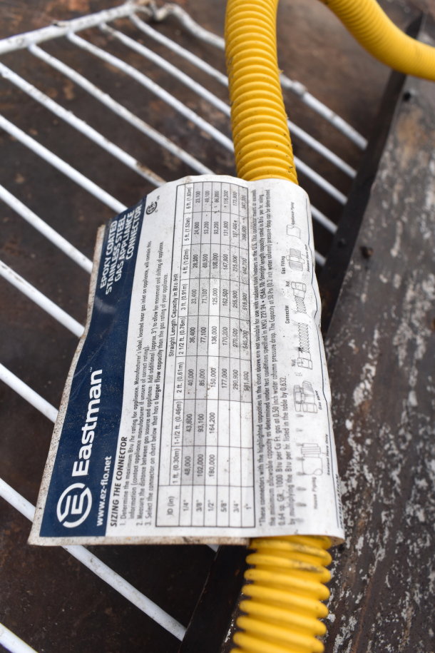Alt text: Eastman stainless steel gas appliance connector label with sizing chart and usage instructions, attached to yellow hose.