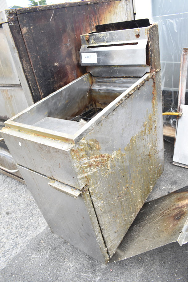 Commercial gas-powered floor fryer with visible signs of wear and grease. Metal construction, includes control panel and vat.