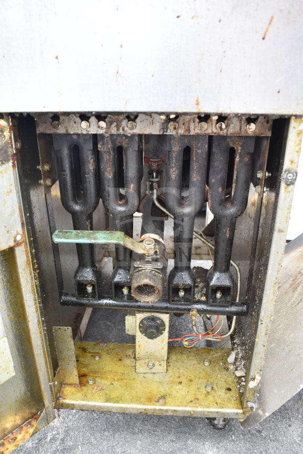 Commercial gas-powered deep fat fryer with visible heating elements and control knob. Signs of wear and rust.