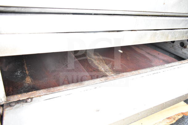 Commercial gas-powered single deck pizza oven, well-used condition, metal exterior, showing baking chamber interior.