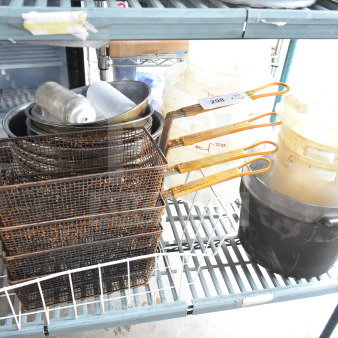 Lot of kitchen items including rusted fry baskets, metal bowls, and marked plastic containers on shelf.