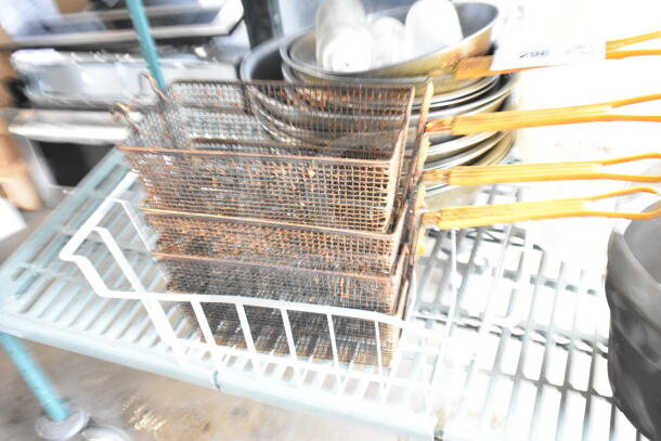 Lot of fry baskets and metal bowls on a shelf, showing signs of rust and wear, suitable for commercial or home use.