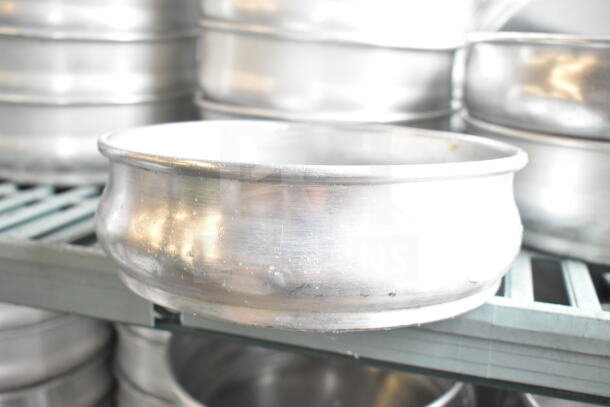 Lot of round metal baking pans in two tiers, showing slight wear, stacked on a shelf. Great for baking needs.