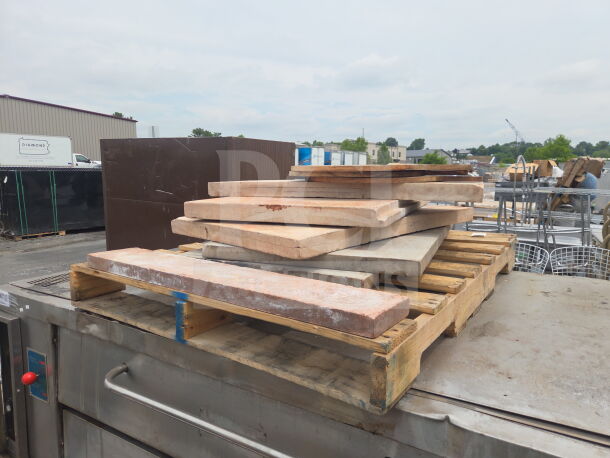 2 commercial gas-powered single deck pizza ovens with cooking stones, shown outdoors on pallets, stainless steel surfaces.