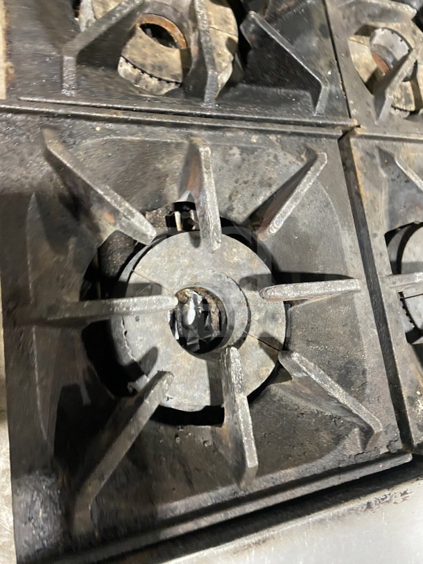 Close-up of a used burner from a Bakers Pride 10 burner range, model 955394604036. Rust and wear are visible.