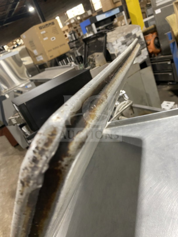 Commercial stainless steel full-size baking sheet pan, slightly worn edges, ideal for bakery or restaurant use.