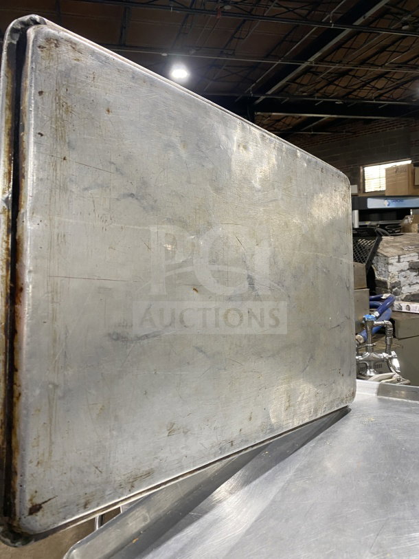 Commercial stainless steel full-size baking sheet pan, used condition, with surface scratches and discoloration.