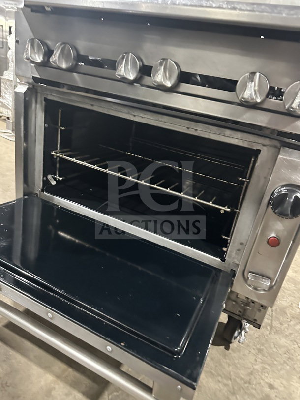 Vulcan commercial stainless steel gas-powered 6-burner range/oven combo with backsplash, wired oven rack, and casters.