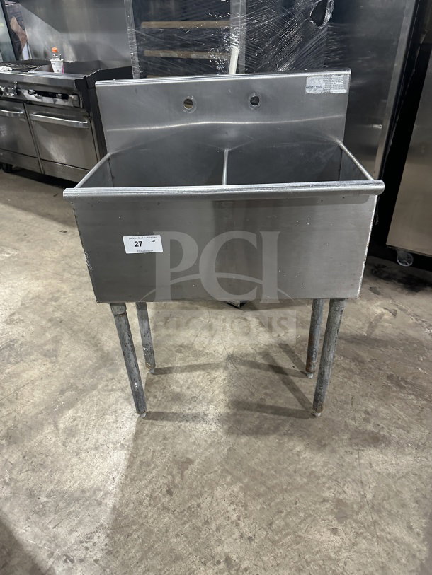 Commercial stainless steel 2-compartment utility sink on legs, SN: 847962, with visible faucets holes and tag.