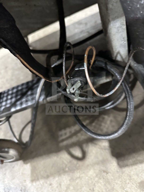 Close-up of electrical cords and metal components beneath Asber PTS-60-16 60 refrigerated prep table on casters.