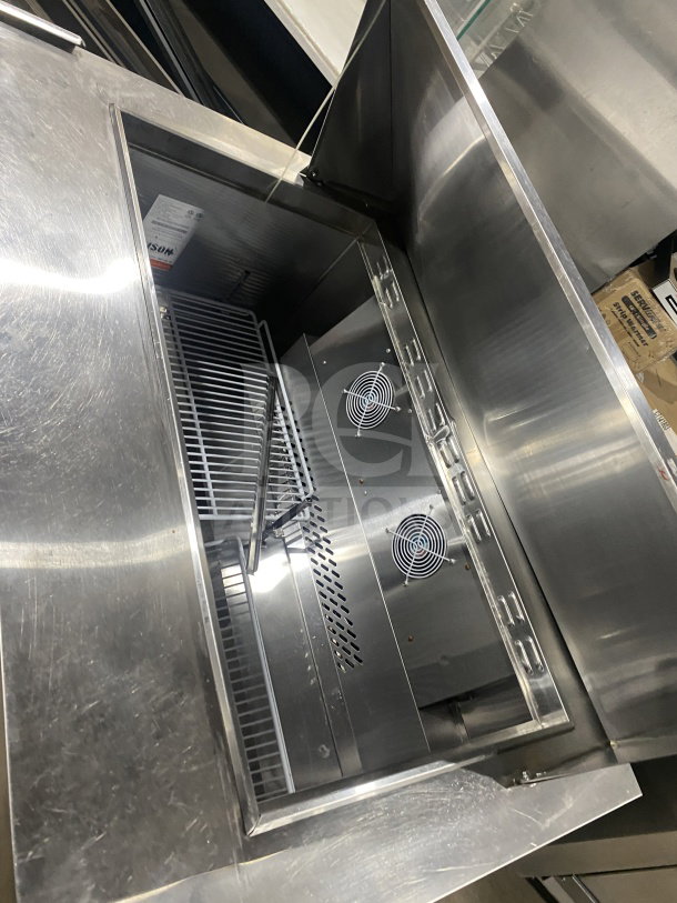 Bison BST4818 stainless steel refrigerated sandwich prep table with poly-coated wire rack, two-door storage, on casters.