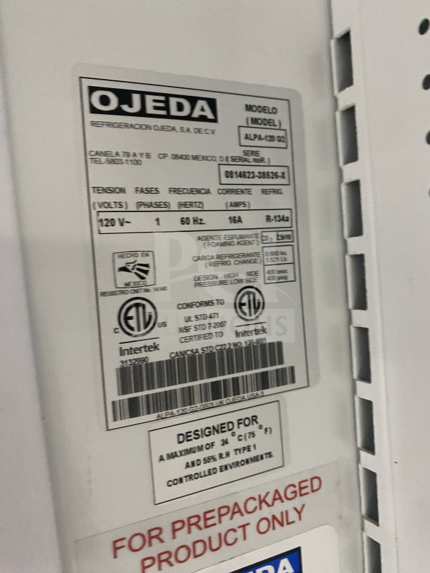 Ojeda ALPA-120H refrigerated merchandiser display case with pull-down night curtain. Features visible model and serial number label.
