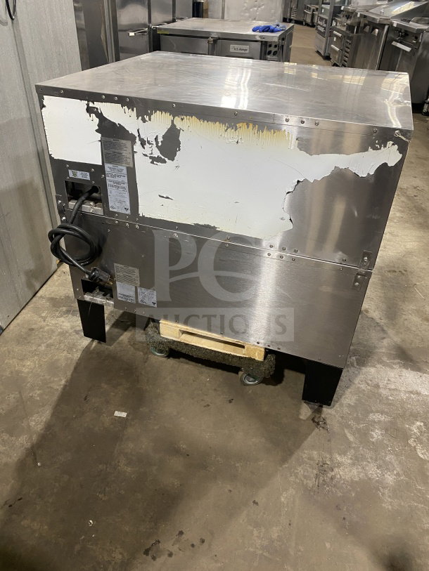 Bakers Pride stainless steel double deck pizza oven on casters, visible wear on exterior, electric powered, label shows model info.