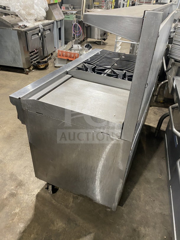 Southbend commercial stainless steel 6-burner range with 24" flat griddle, two full-size ovens, and poly wired rack on casters.