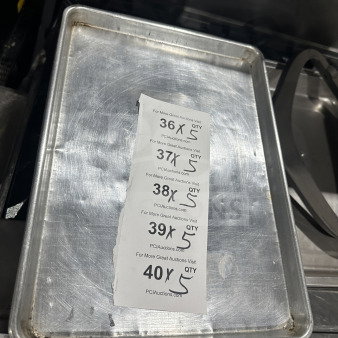 Commercial stainless steel baking sheet pan, lightly used, visible wear. Includes auction tags indicating quantity five.