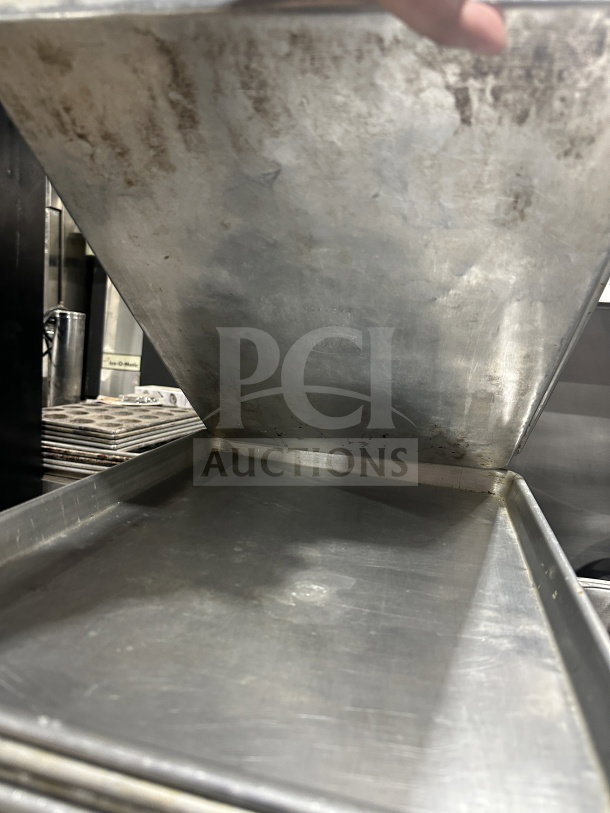 Commercial stainless steel baking sheet pan in used condition, visible wear, durable material.