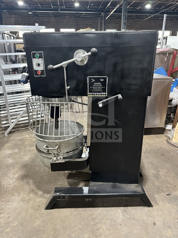Blakeslee commercial black electric planetary mixer with stainless steel bowl guard, mixing bowl, and spiral hook. On legs.