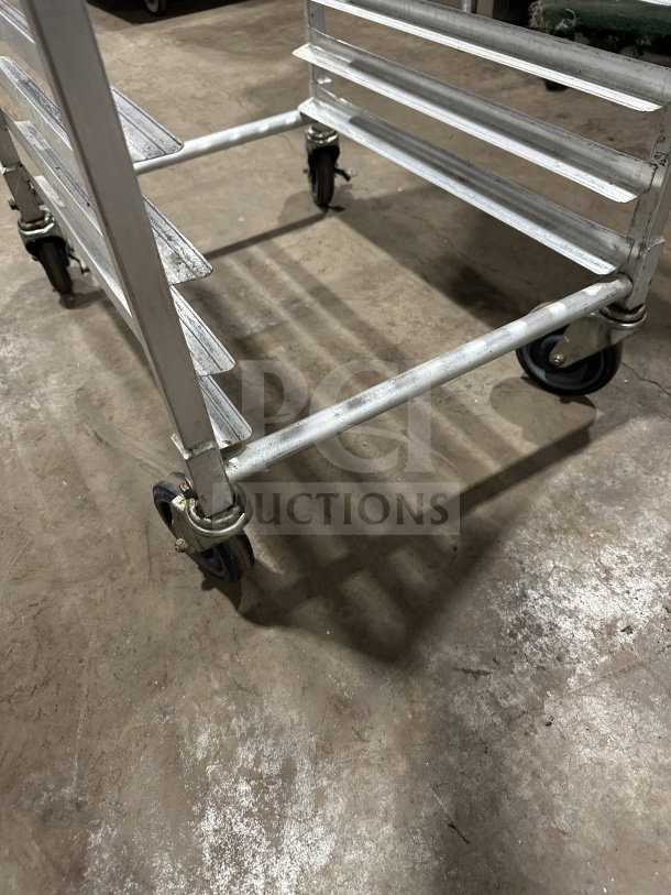 Commercial stainless steel pan rack on casters, small size, heavy-duty, with multiple shelves, in used condition.
