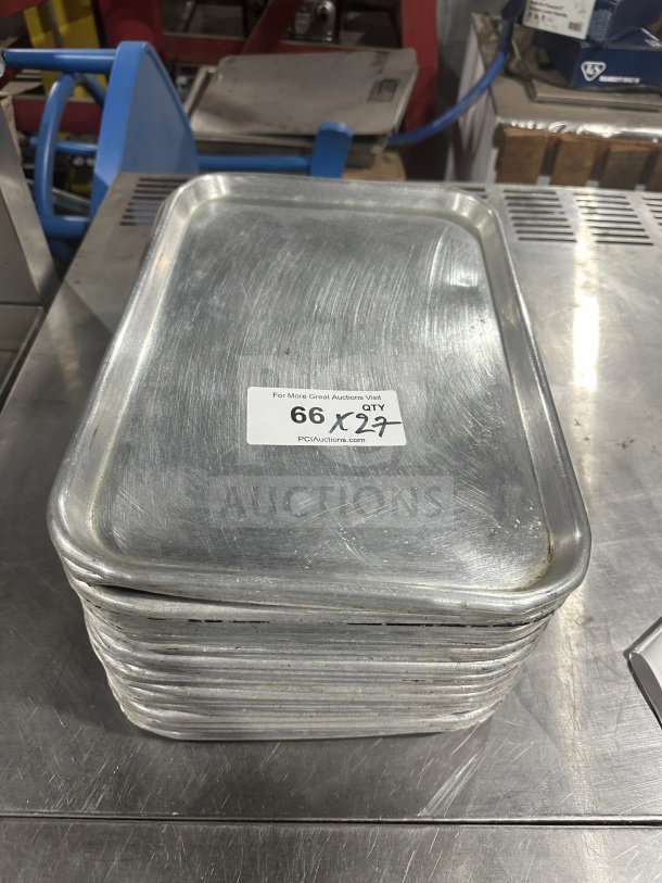 Stack of commercial heavy-duty stainless steel display trays, showing wear. Label indicates quantity 27, auction number 66.