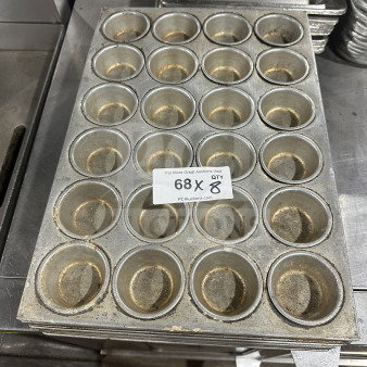 Commercial heavy-duty stainless steel 24-cup muffin pan, used condition, stack of eight with auction label visible.