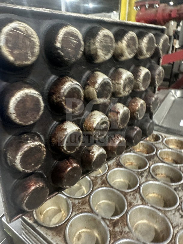 Commercial heavy-duty 24-cup stainless steel muffin pan, well-used, visible wear, ideal for large-scale baking needs.