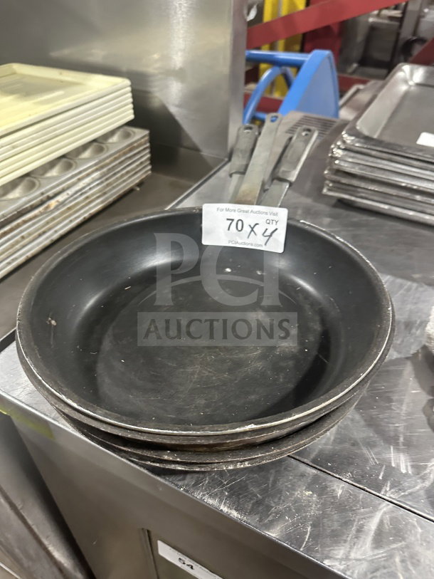 Commercial heavy-duty aluminum non-stick fry pans, used condition, set of four. Auction lot 70X4 tag visible.