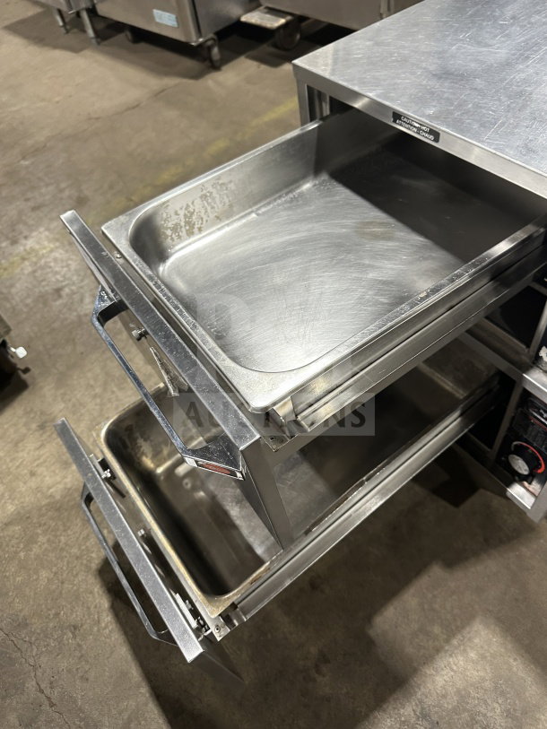 Hatco HDW2W stainless steel 2-drawer warmer, electric, 120V, on legs, clean interior, visible "Caution Hot" label.