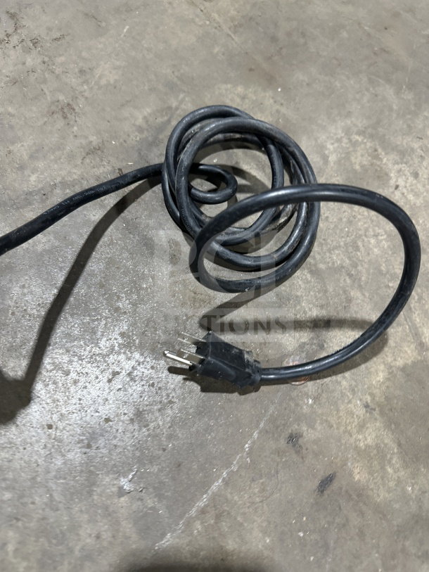 Black power cord with three-pronged plug on concrete floor, part of Hatco HDW2W warmer unit.