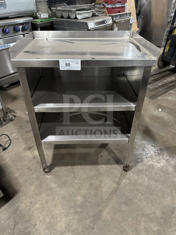 Commercial stainless steel double undershelf equipment stand on casters, used condition, features flat top and undershelves.
