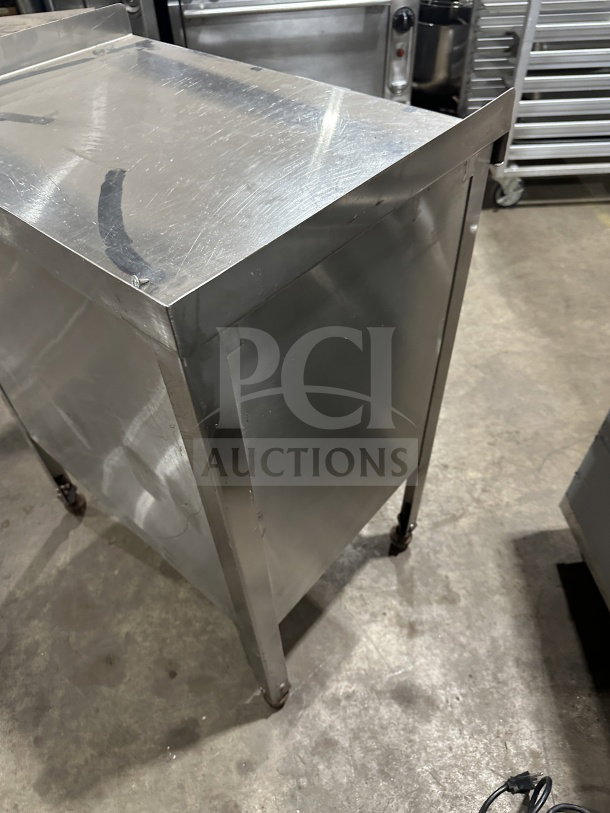 Commercial stainless steel equipment stand with double undershelf and casters; used condition.