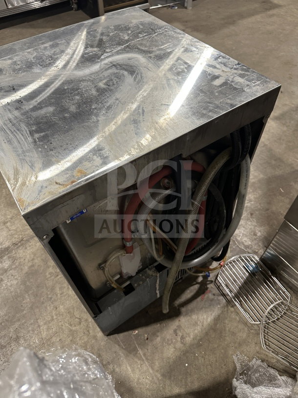 Champion UH130B-M4 stainless steel undercounter dishwasher, visible wiring and hoses, used condition.