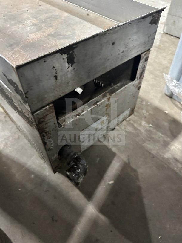 Commercial stainless steel gas-powered countertop flat top griddle with visible wear and rust; mounted on legs for stability.